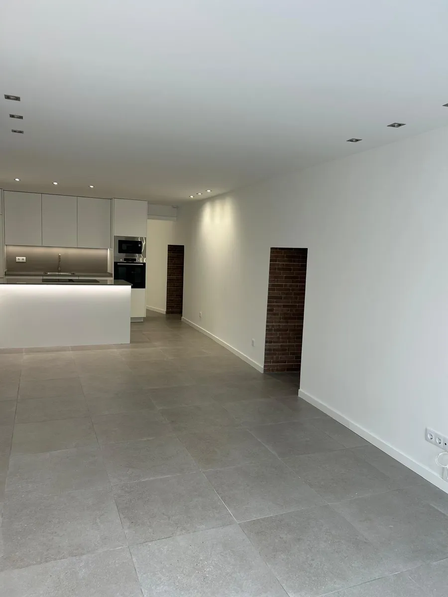 Sala ampla renovada com pavimento novo e iluminação embutida